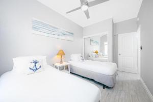 een witte slaapkamer met 2 bedden en een plafondventilator bij Stunning Ocean Views - Recently Renovated Home & Warm Sunsets in San Diego