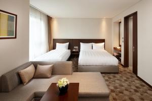 ウルサンにあるLOTTE City Hotel Ulsanのベッド2台とソファが備わるホテルルームです。