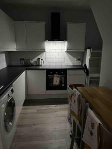 a kitchen with white cabinets and a stove top oven at COSY 1 -The Lodge in Bury