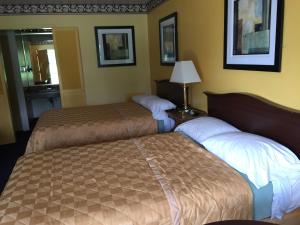 a hotel room with two beds and a lamp at Norwalk Inn in Norwalk
