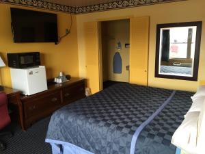 a bedroom with a bed and a tv and a window at Norwalk Inn in Norwalk