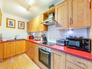 une cuisine avec des placards en bois et des comptoirs rouges dans l'établissement Durham Oasis Apartment - Uk46017, à Durham