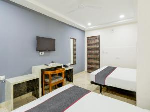 a bedroom with two beds and a desk and a tv at Townhouse Hotel Rio in Hyderabad