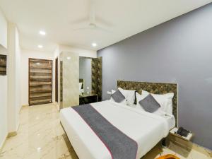 a bedroom with a large white bed with pillows at Townhouse Hotel Rio in Hyderabad