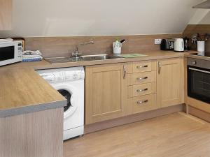 a kitchen with a sink and a washing machine at The Barn in Dalmally