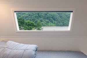Chuncheon Healing Bridge في تشنتشون: نافذة كبيرة في غرفة بيضاء مع سرير