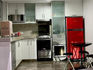 eine Küche mit weißen Schränken und einem roten Kühlschrank in der Unterkunft Departamento en Asia Chocaya in Asia