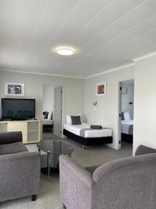 a hotel room with a bed and a couch and a tv at Kensington Motel in Whangarei