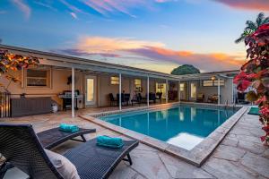 a swimming pool with two chairs and a patio at Music Lovers Villa, 4BD, 3BA, Pool, Game Room Outdoor Projector in Pembroke Pines