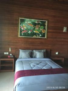 a bedroom with a bed with a painting on the wall at Sakya Garden Villa in Toyapakeh