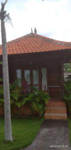 a house with a palm tree in front of it at Sakya Garden Villa in Toyapakeh