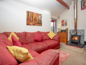 salon z czerwoną kanapą i kominkiem w obiekcie Bulls Cottage w mieście Bodmin
