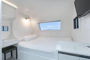 a small white room with a bed and a window at Pohang Uni's Sea Guryongpo in Pohang