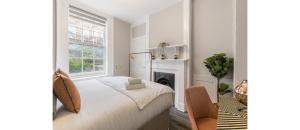 a white bedroom with a bed and a fireplace at Serenity in the City: Best 5BR Home in Whitechapel in London