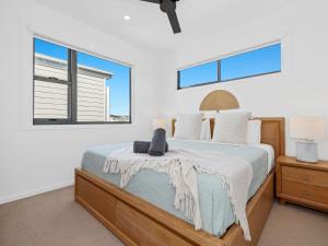 a bedroom with a bed and two windows at Serenity Sands Townhouse in Kingscliff