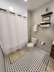 a bathroom with a toilet and a black and white tile floor at *The Stunning *King Suite* Heart of Towson in Towson