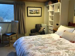a bedroom with a bed and a chair and a window at The Nook in Arthur's Pass