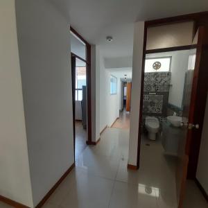 a bathroom with a toilet and a door to a hallway at Hepico Departamentos Piura in Piura