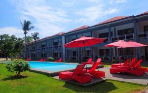un hôtel avec des chaises rouges et des parasols à côté d'une piscine dans l'établissement ANGEL'S DREAM RESIDENCE, à Panglao