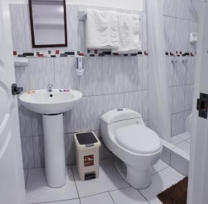 a white bathroom with a toilet and a sink at Cusco de mis Sueños Hostal - II in Cusco