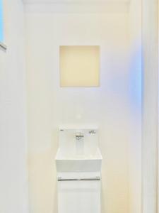 uma casa de banho branca com um lavatório e uma parede branca em MEGUFUJI PLUS+ em Fujiyoshida
