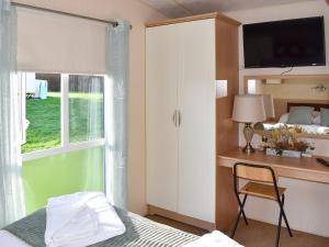 een slaapkamer met een bed, een bureau en een raam bij Solent Village 13-uk44072 in Cowes