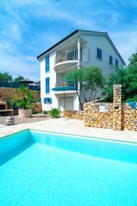 a villa with a swimming pool in front of a house at Family friendly house with a swimming pool Garica, Krk - 19507 in Kras