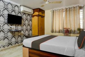 a bedroom with a bed and a tv on a wall at OYO 82148 Hotel Galaxy Residency kalyani nagar in Pune