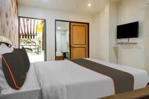 OYO 82148 Hotel Galaxy Residency kalyani nagar في بيون: غرفة نوم مع سرير وتلفزيون على الحائط