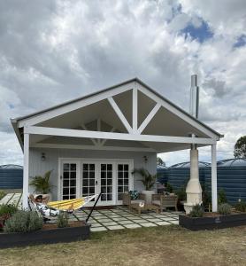 ein weißes Haus mit einer Veranda und einer gelben Hängematte in der Unterkunft Lusso Retreats in Moffatdale