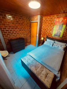 1 dormitorio con 1 cama en una pared de ladrillo en Casa Aconchego da Serra - Gravatá - PE, en Gravatá