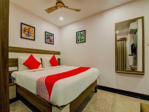 a bedroom with a bed with red pillows and a mirror at Pratibha Grand in Vijayawāda