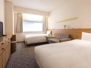 a hotel room with two beds and a television at Hotel Gracery Ginza in Tokyo