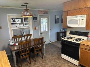 een keuken met een fornuis en een tafel met stoelen bij Barbee Chain Lake Access! 3 Bedroom Cozy Cottage in North Webster