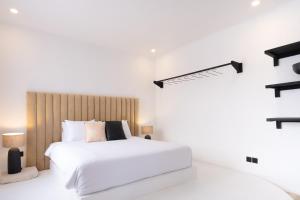 Schlafzimmer mit einem weißen Bett mit einem Kopfteil aus Holz in der Unterkunft Casa Art Ubud in Ubud