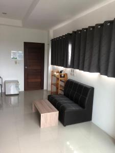 a living room with a black couch and a coffee table at Sleep inn Samui in Choeng Mon Beach