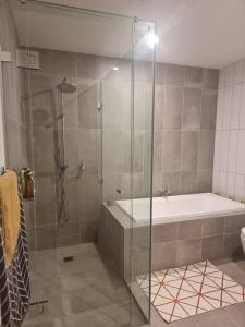 a bathroom with a shower with a tub and a glass shower stall at 2 Bedrooms Aptmt with Ocean View in Geelong