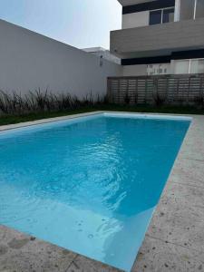 a blue swimming pool in front of a house at Departamento con alberca y playa cerca Veracruz Rock in Boca del Río