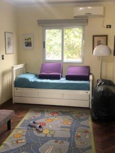 Cama con almohadas moradas en una habitación con ventana en Casa Pilar en Yerba Buena