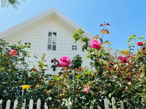 a white house behind a white fence with roses at HomeTa Homestay in Bao Loc