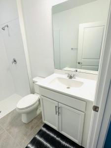 y baño con lavabo, aseo y espejo. en Escape getaway suite, en Port Saint Lucie