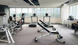 a gym with several exercise bikes in a room with windows at Brittany Hotel BGC in Manila
