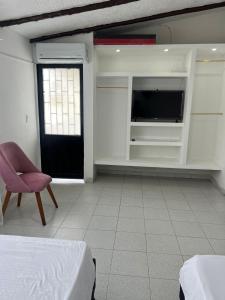a bedroom with a bed and a tv and a chair at Jerusalén in Mariquita