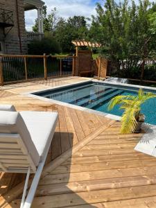 a swimming pool with a wooden deck and a white bench at La Demeure du Capitaine in Neuville