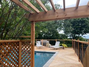 una terraza de madera con piscina y pérgola en La Demeure du Capitaine, en Neuville