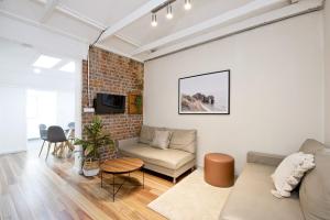 a living room with a couch and a brick wall at A Quaint Darlinghurst Cottage in Sydney
