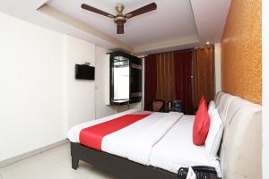 a bedroom with a large bed with red pillows at Capital O Hotel Orchid Inn in Kankhal