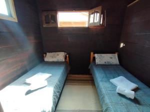 2 camas en una habitación pequeña con ventana en La Cabañita Córdoba en Villa Rumipal