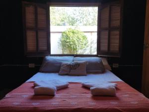 1 cama con 2 almohadas y ventana en La Cabañita Córdoba en Villa Rumipal
