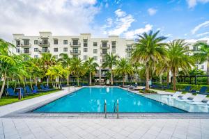 a hotel with a swimming pool and palm trees at Modern 2 Bed in the Heart of Doral Free Parking in Hialeah Gardens